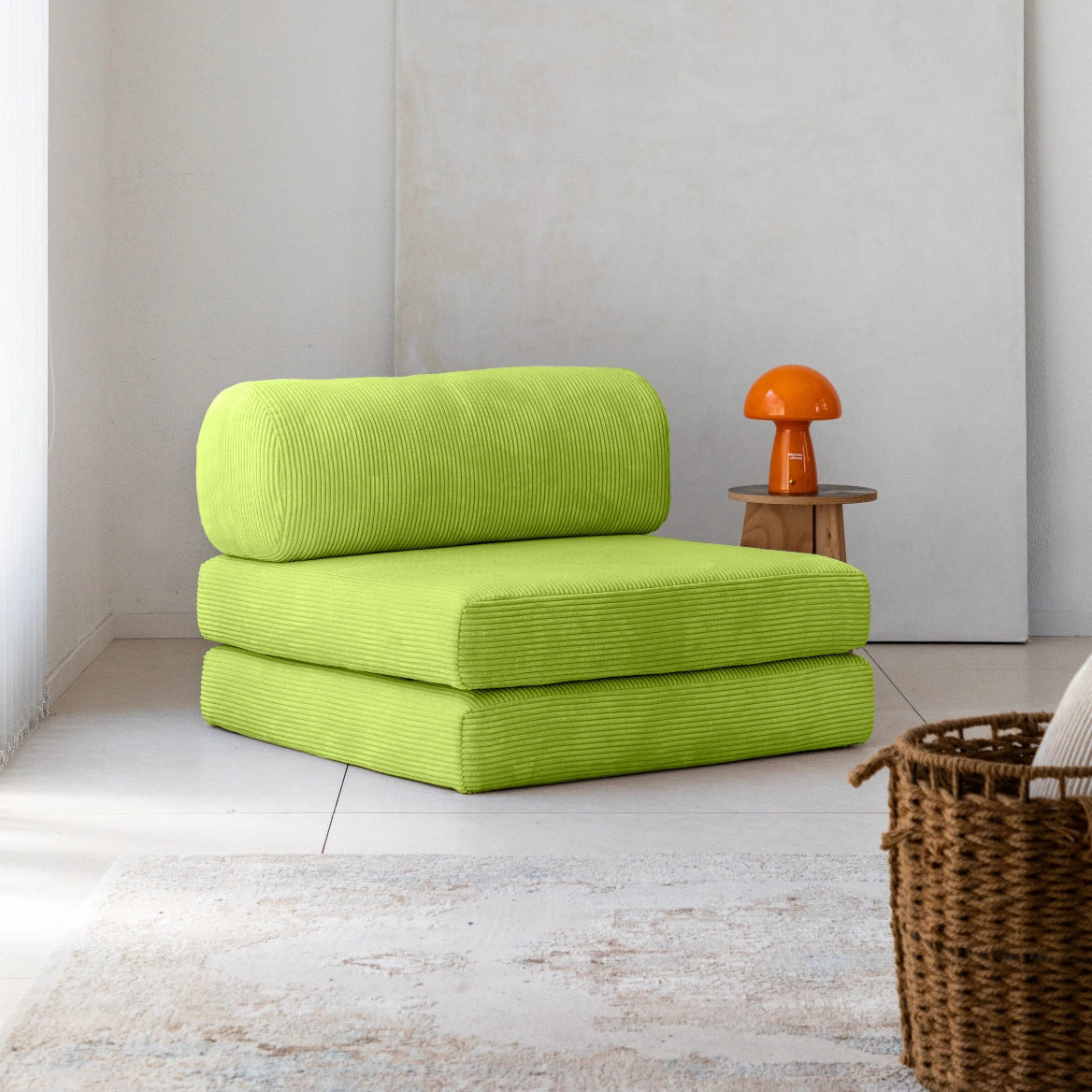 Green modular sofa in a minimalistic room with a white wall and wooden floor.