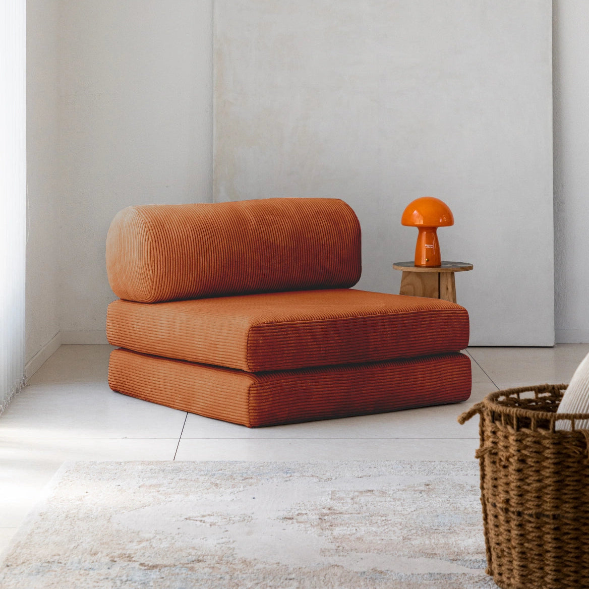 Orange lounge chair in a minimalistic room with a side table and basket.