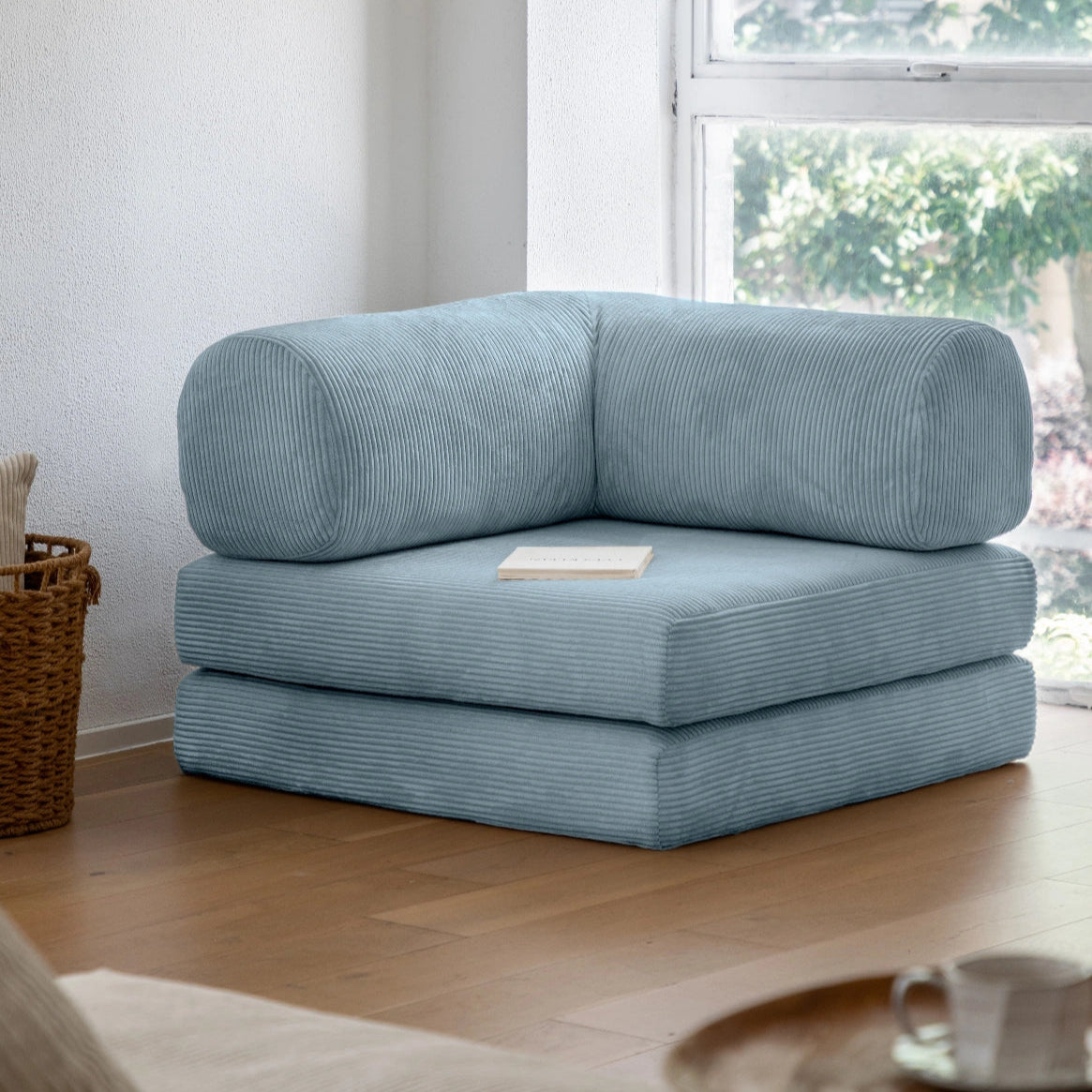 Light blue corner sofa in a room with a window and wooden floor.