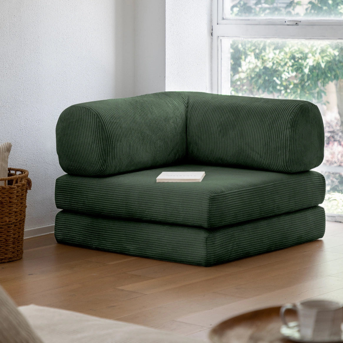 Green sectional sofa in a room with a window and wooden floor.