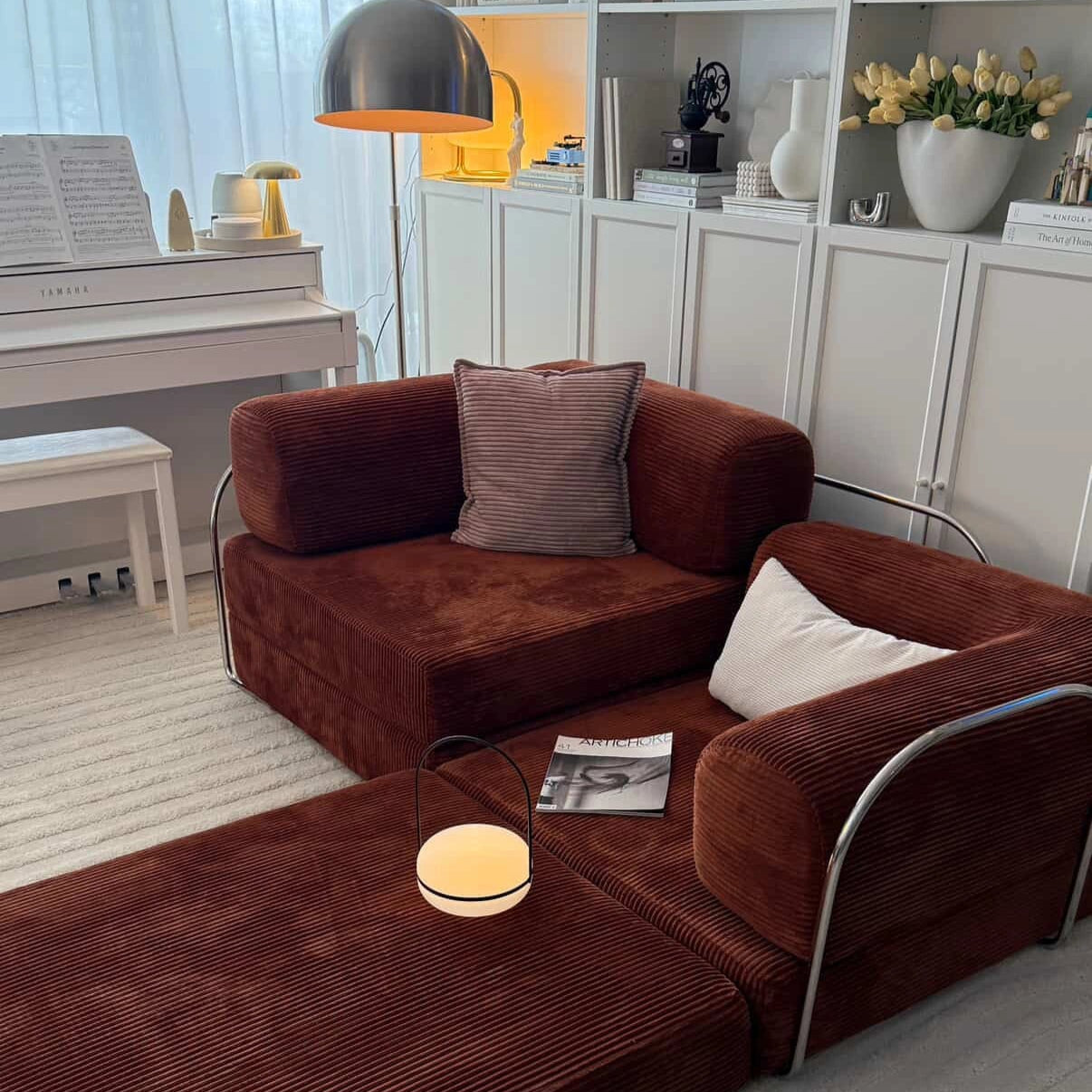 chestnut sectional sofa in a living room with a book and small table lamp.