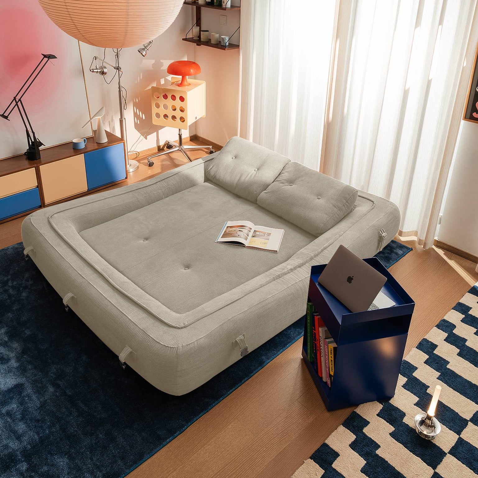 Modern bedroom with a gray air mattress on a wooden floor, surrounded by furniture and decor.