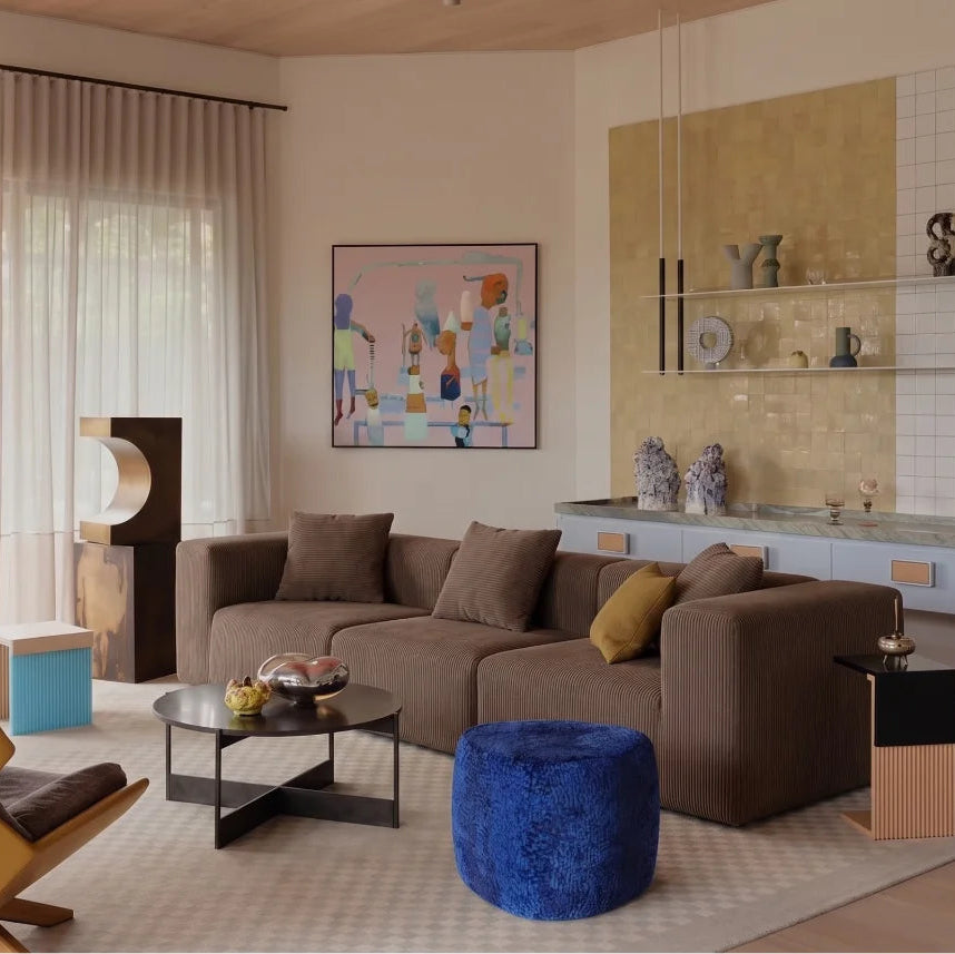 Modern living room with a brown sofa, yellow chair, and blue ottoman.