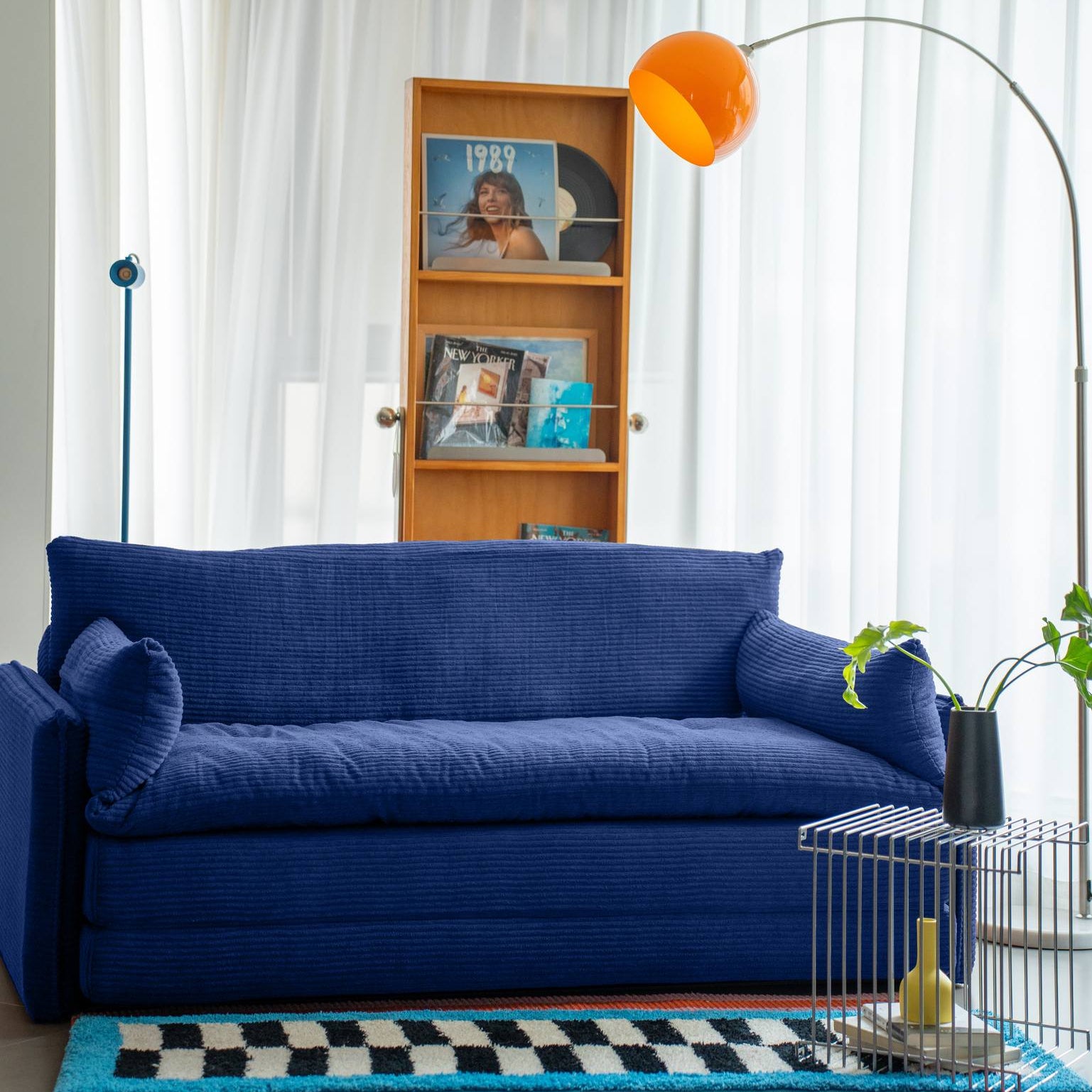 Modern living room with a blue sofa, bookshelf, and decorative items.