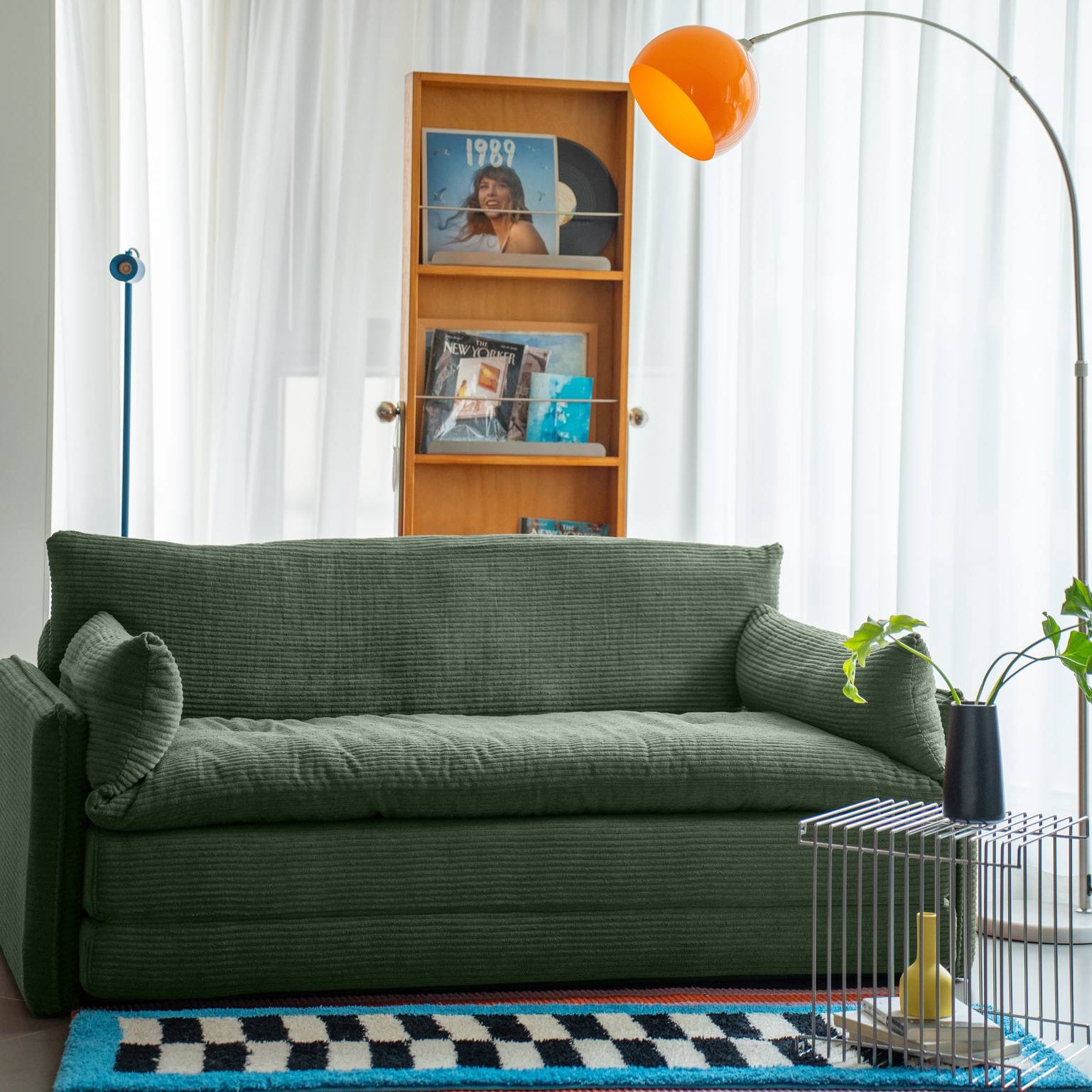 Living room with a green sofa, bookshelf, and decorative items.