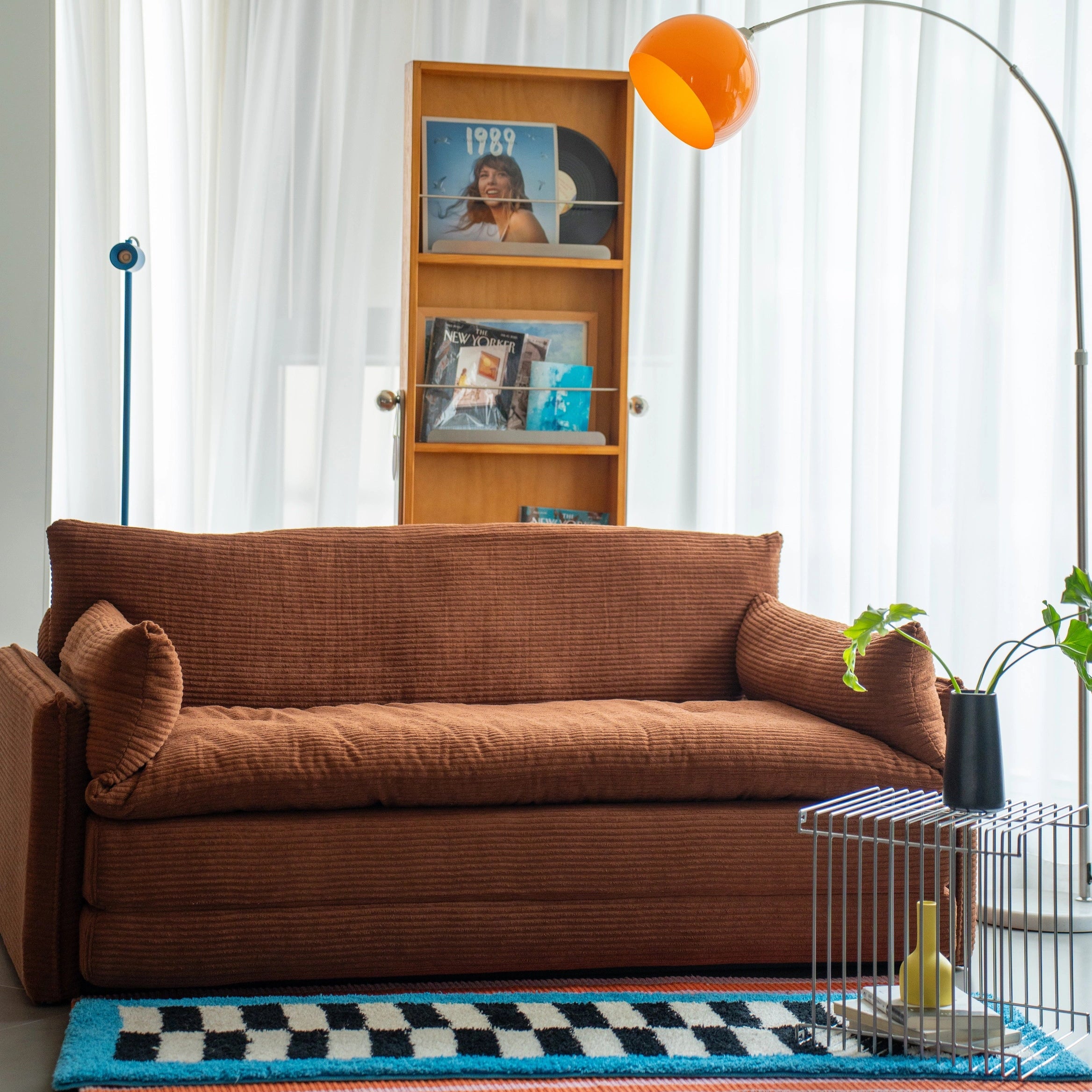 Living room with brown sofa, bookshelf, and decorative items.