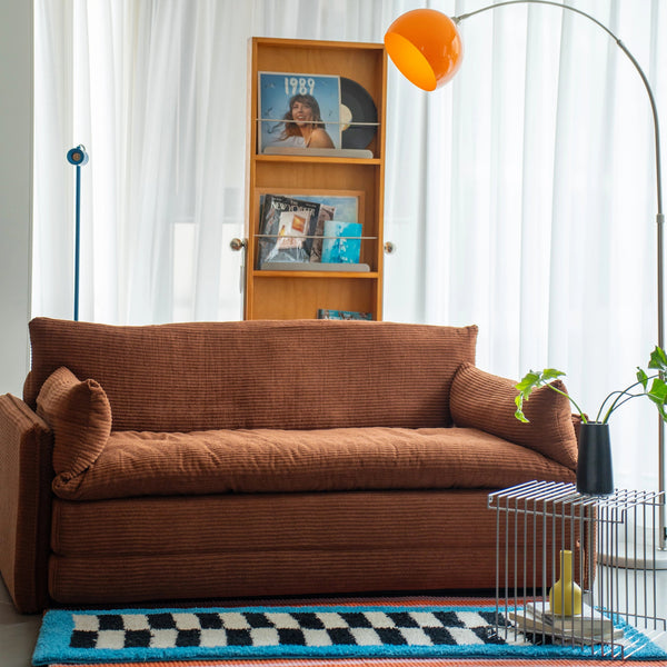 Living room with brown sofa, bookshelf, and decorative items.