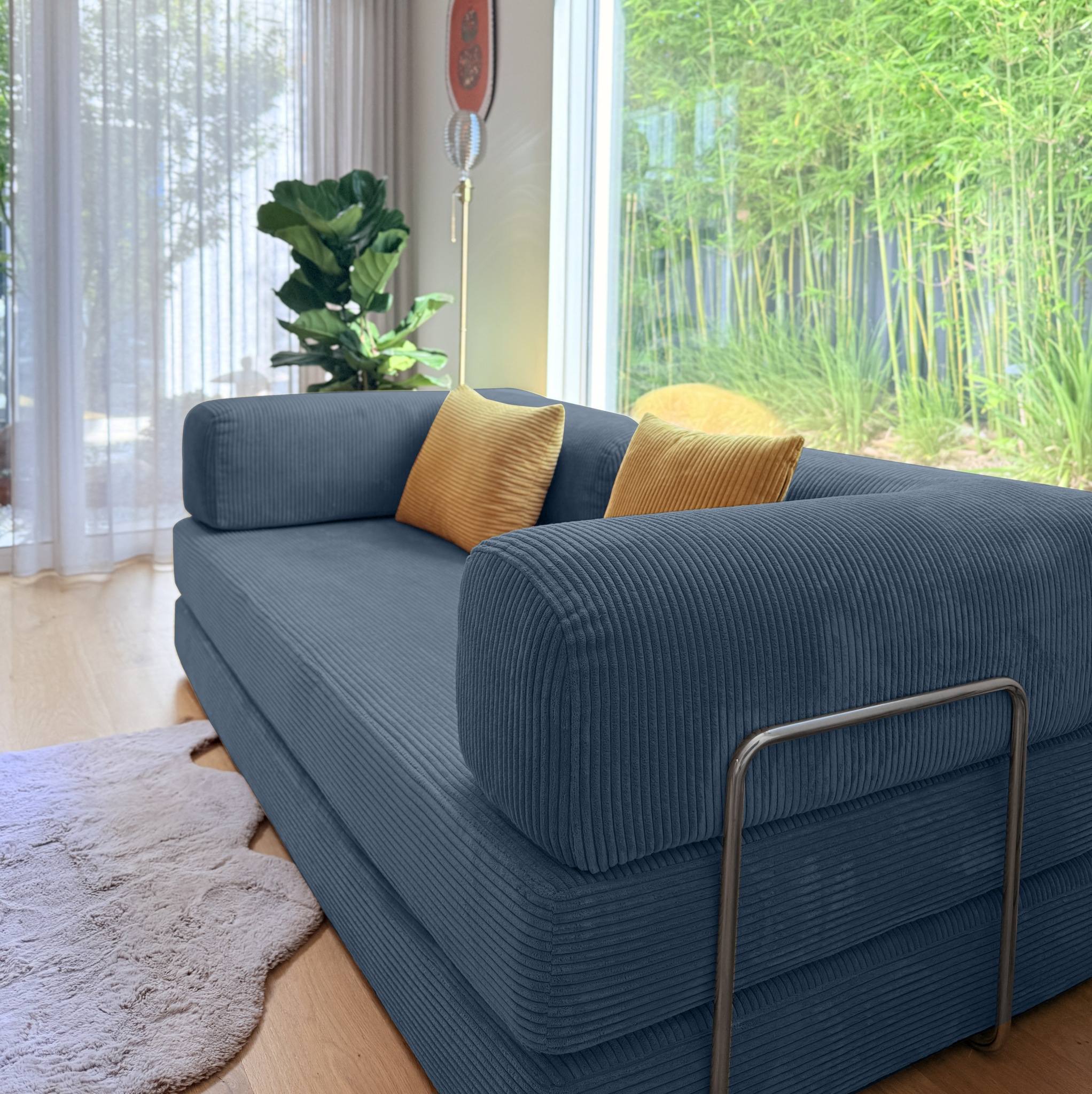 Blue sofa with gold cushions in a room with large windows and plants