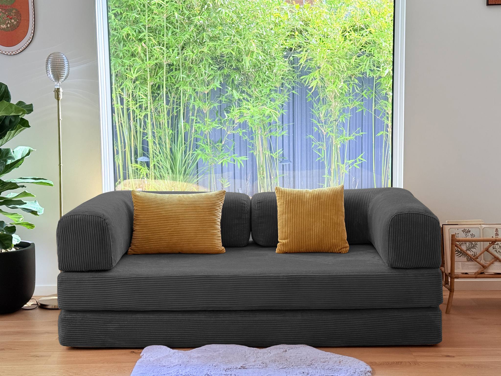 Gray sofa with yellow cushions in a room with large windows and plants.