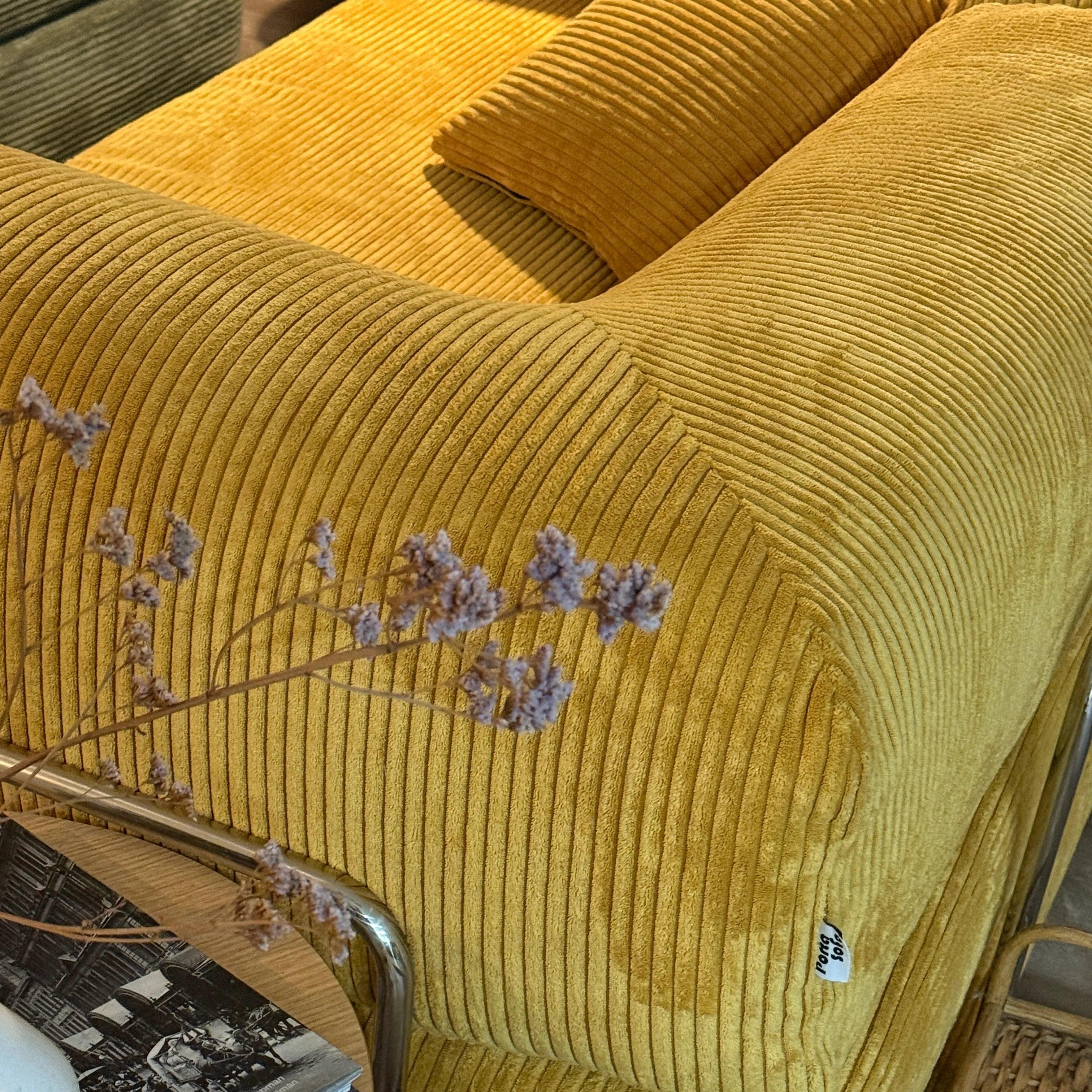 Close-up of a yellow textured sofa with dried flowers on a chair.