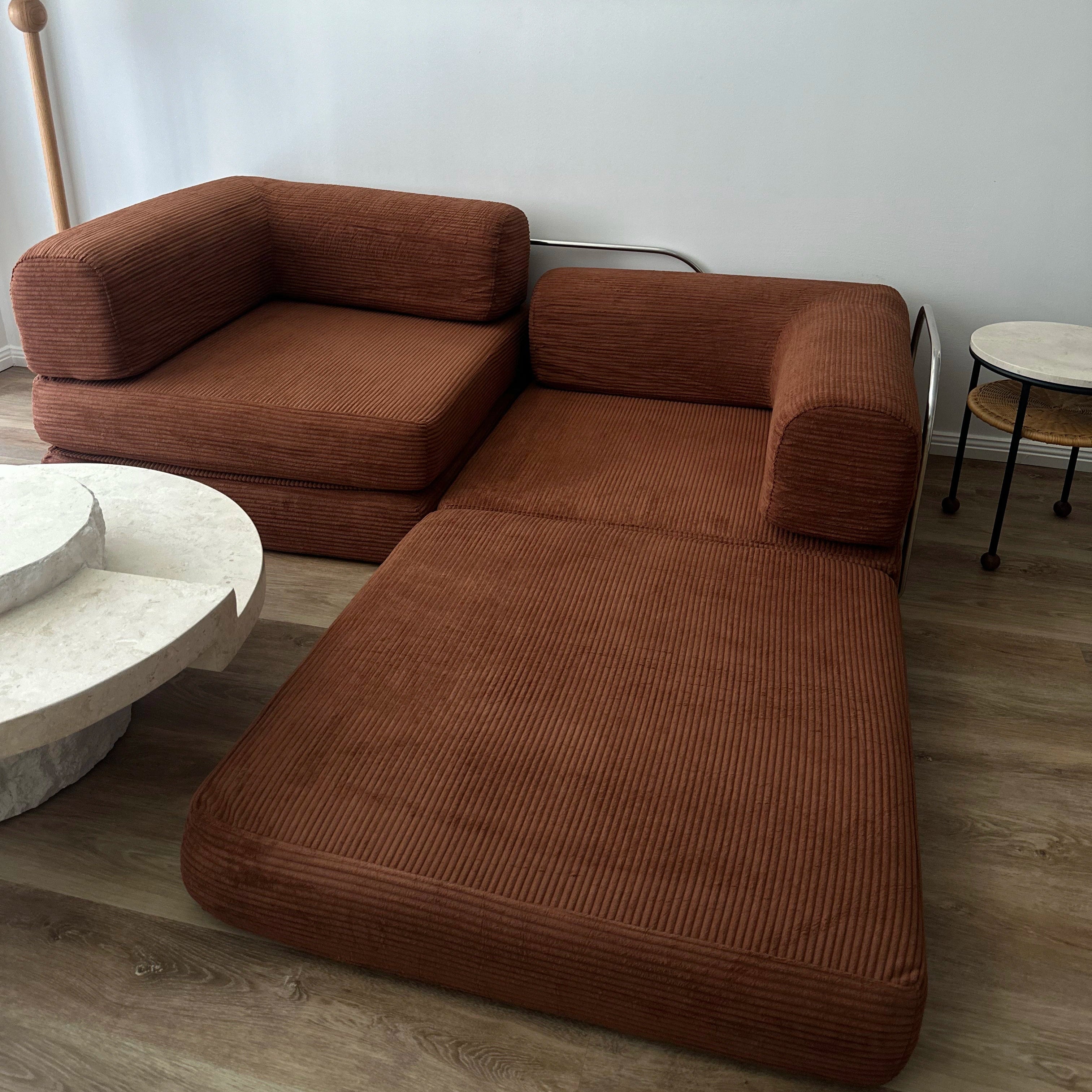 Brown sectional sofa in a living room with a white wall and framed artwork.