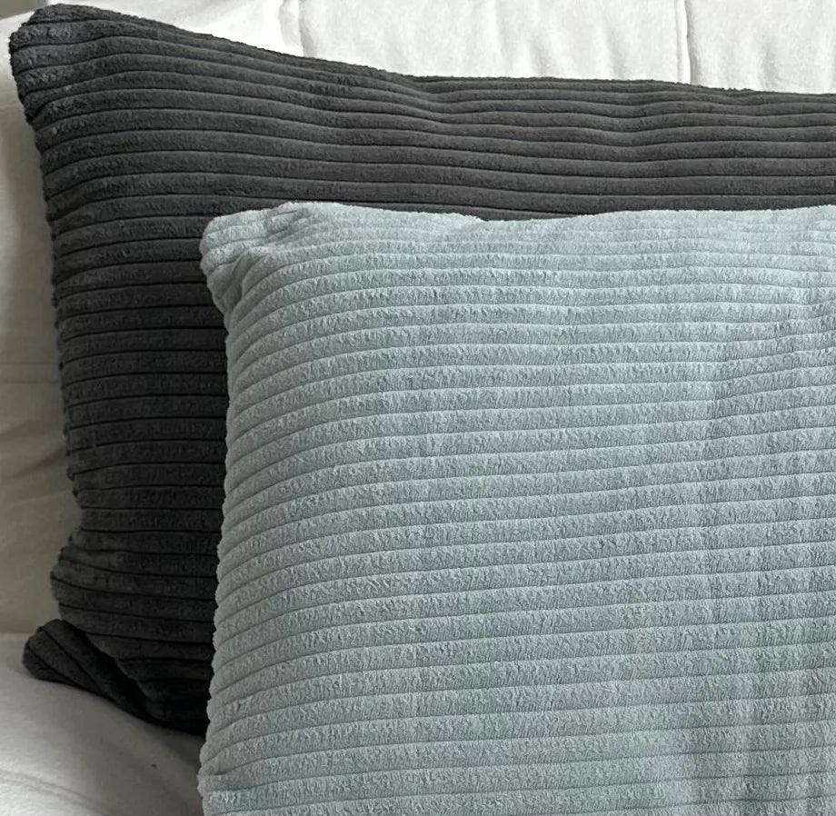 Two textured pillows, one gray and one light blue, on a white background.