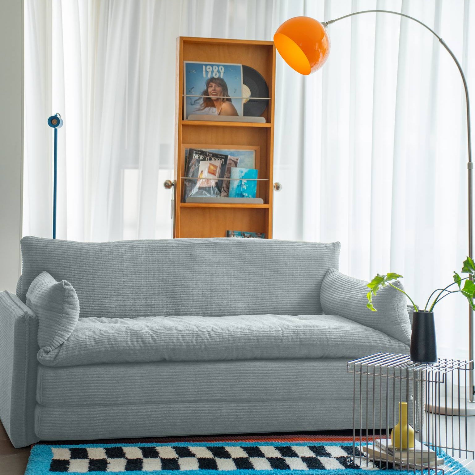 Modern living room with a gray sofa, bookshelf, and decorative elements.