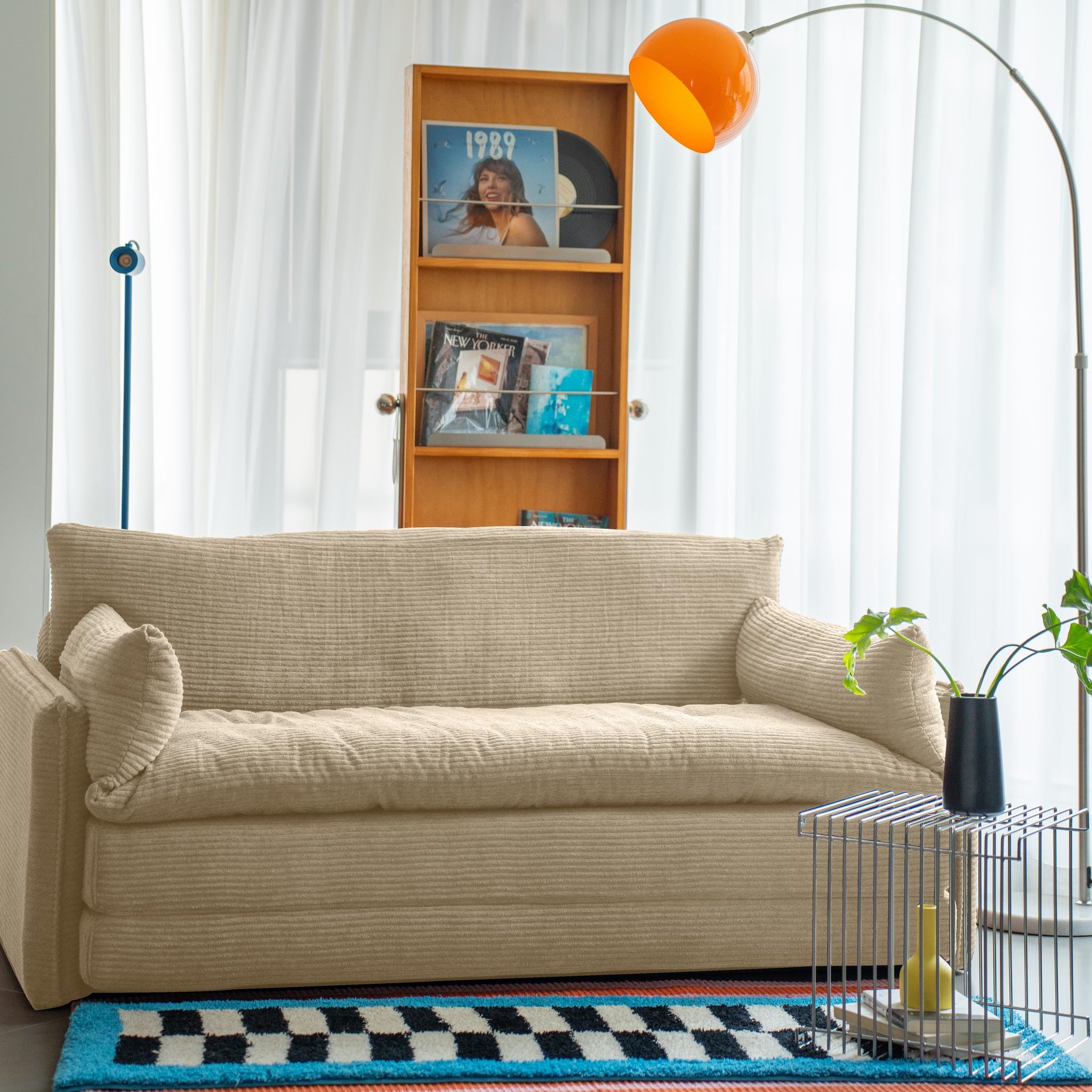 Beige sofa in a living room with a bookshelf, lamp, and decorative items.