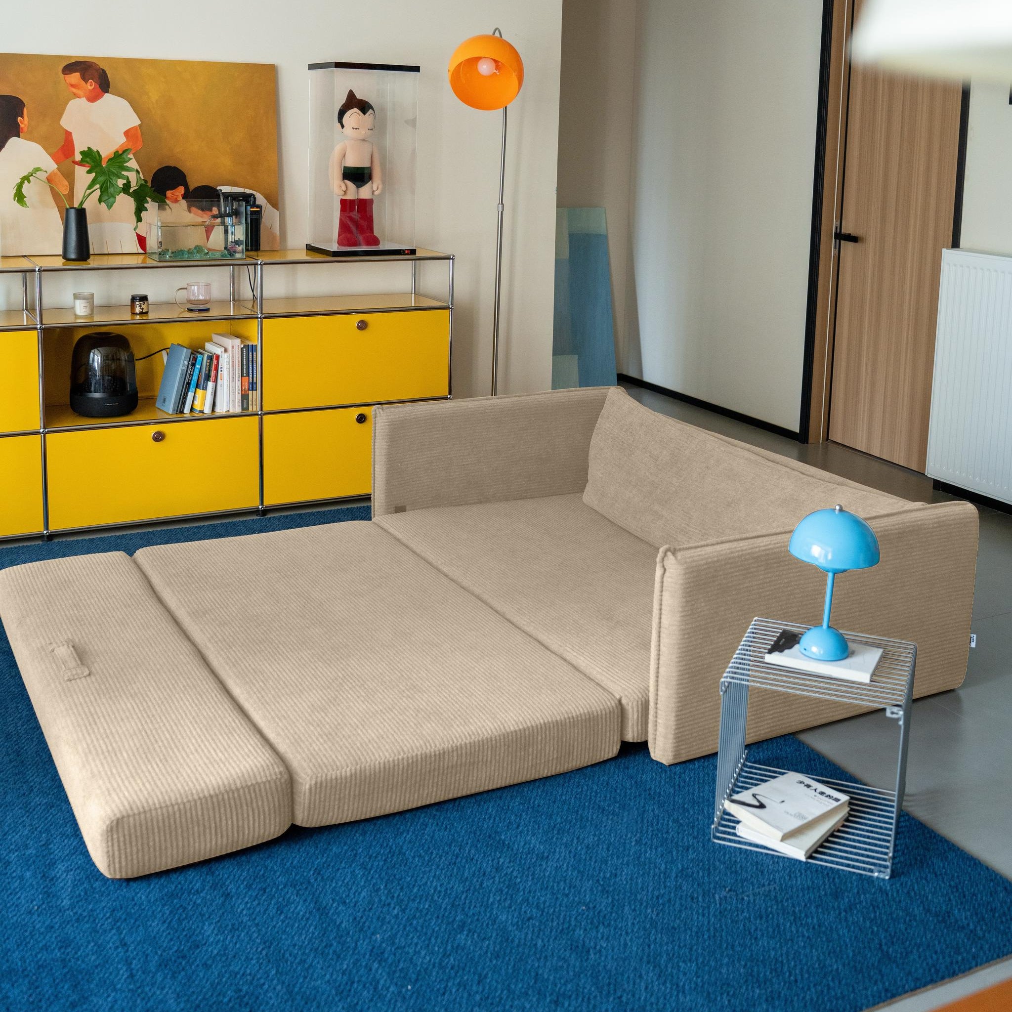 Modern living room with beige sectional sofa, yellow cabinet, and blue rug.