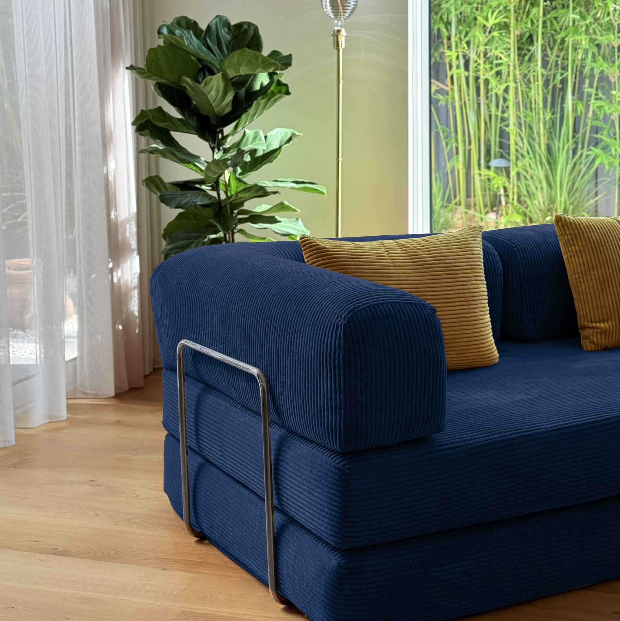 Blue sofa with yellow cushions in a room with plants and curtains