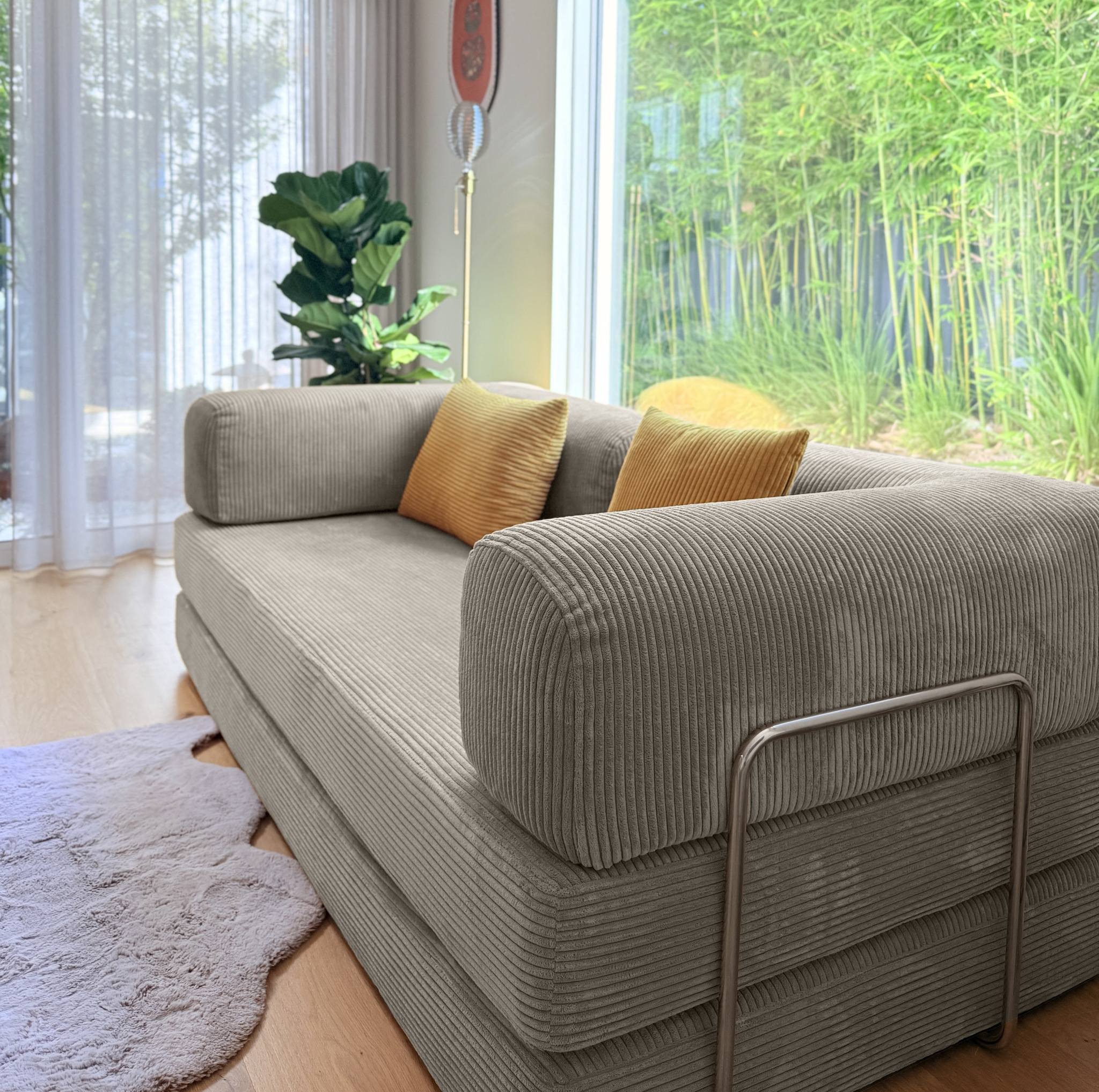 Gray sofa with yellow cushions in a room with large windows and plants