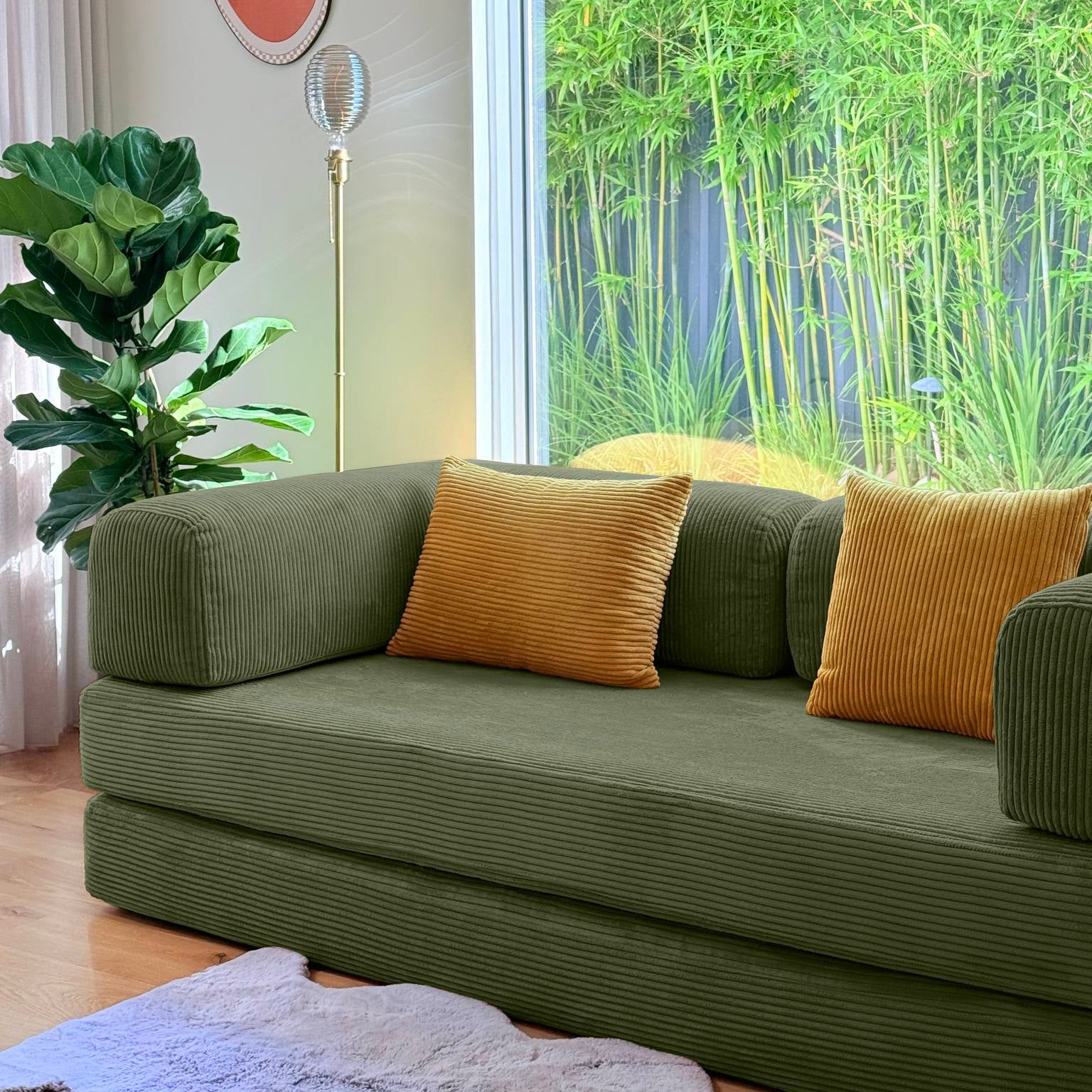 Green sofa with orange cushions in a room with bamboo view