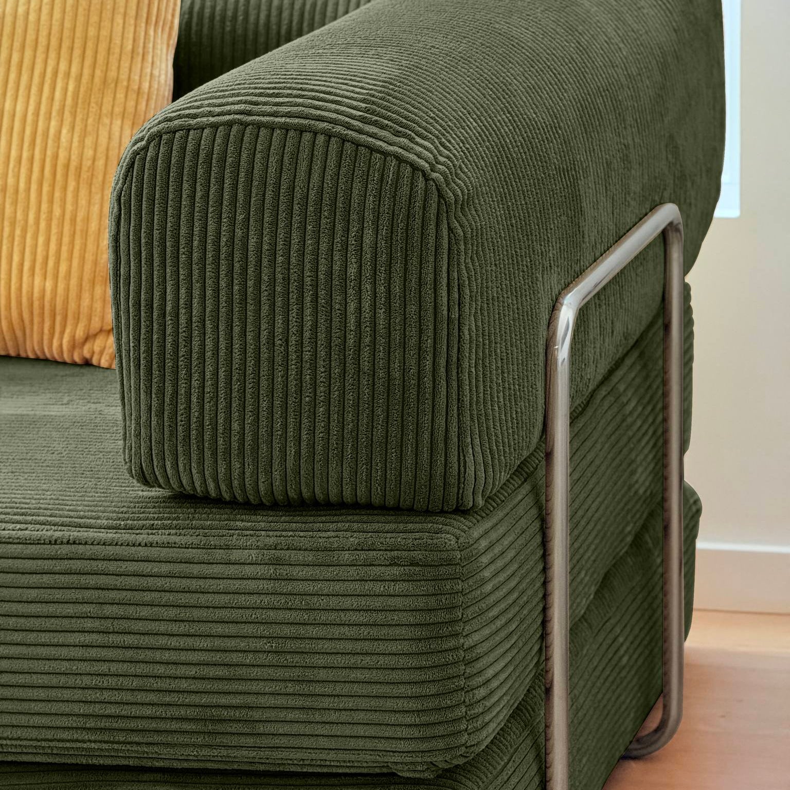 Green corduroy sofa with a yellow pillow against a window with blue curtains.