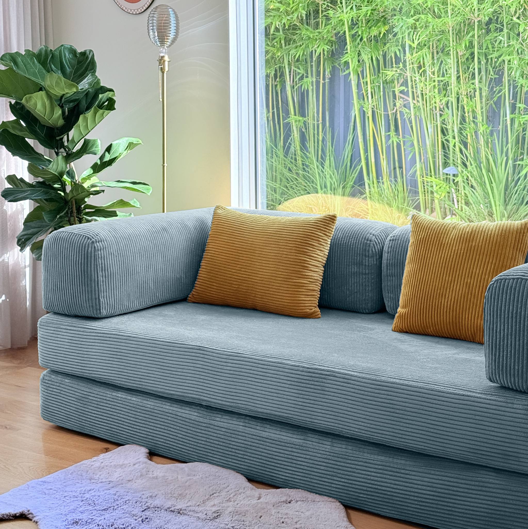 Blue sofa with yellow pillows in a room with plants and a window.