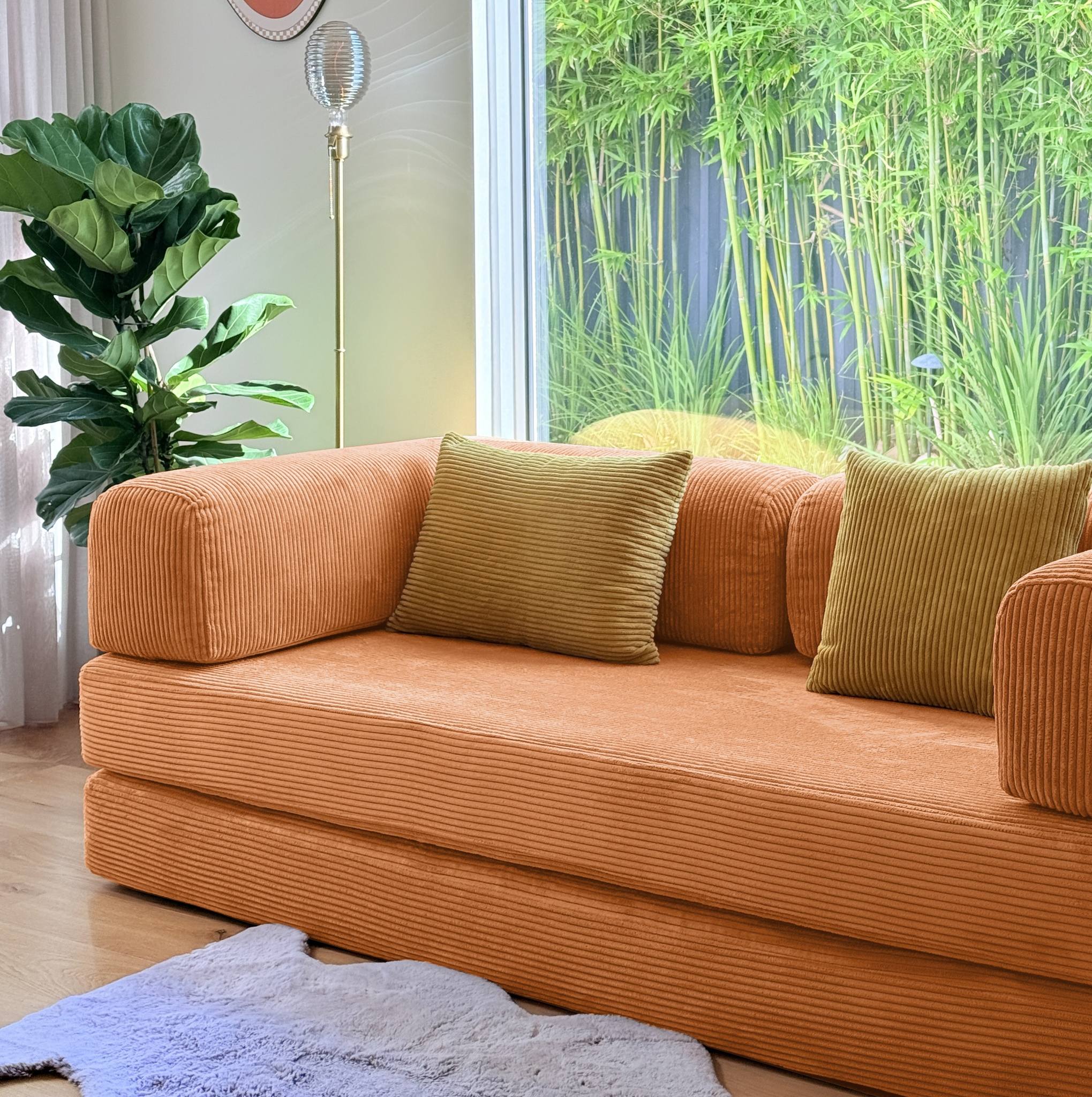 Orange sofa with green pillows in a room with bamboo view